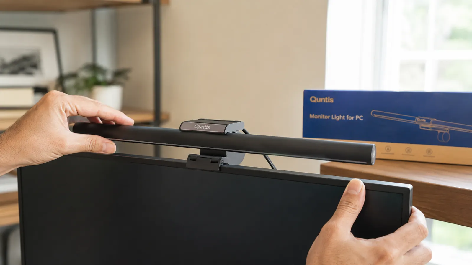 Close-up of a Quntis monitor light bar clipped to the top edge of a monitor, USB cable routed neatly to the back