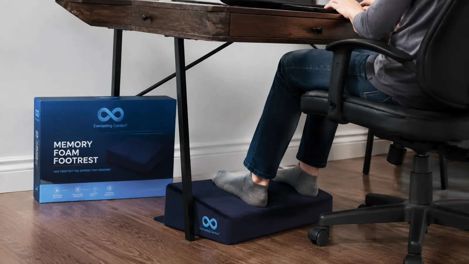 Stockinged feet resting on the Everlasting Comfort memory foam footrest under a standing desk converter