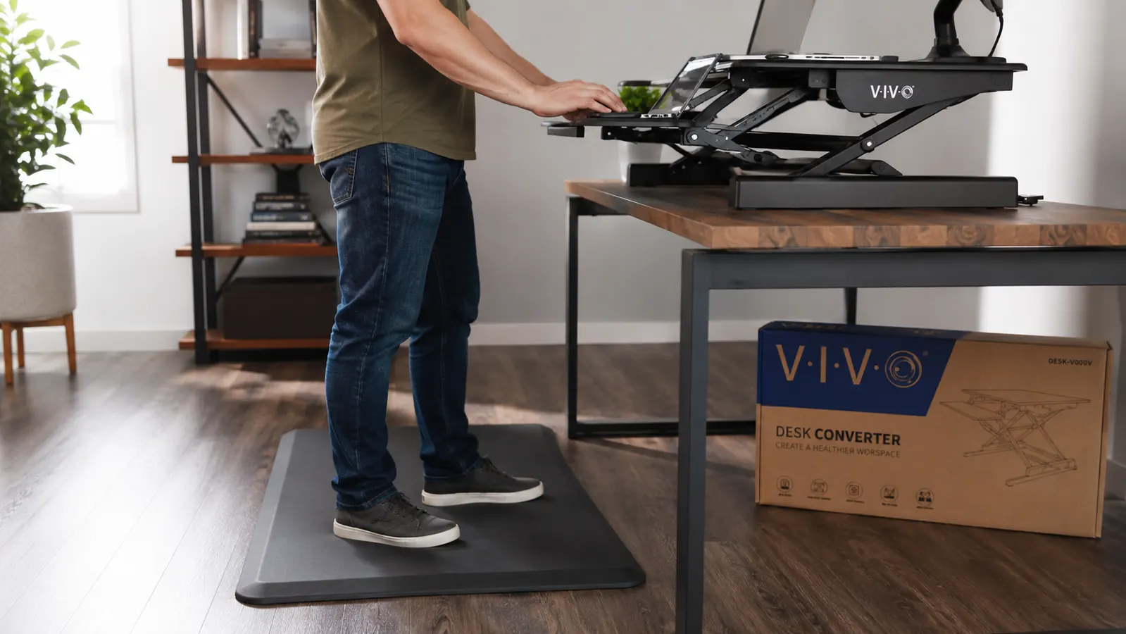 Anti-fatigue mat placed in front of a standing desk converter, person standing with proper posture