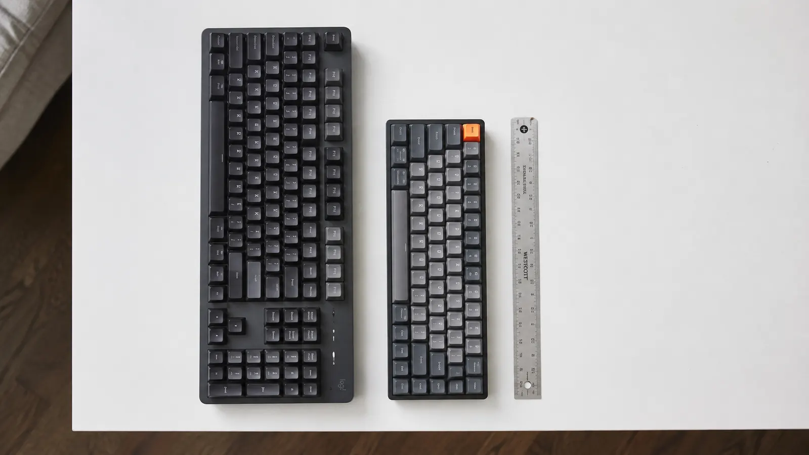 Side view comparison of a large full-size keyboard versus a compact keyboard showing the size difference